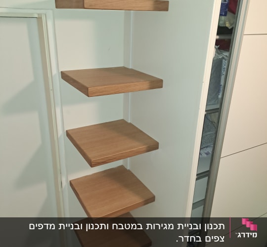 מדפי עץ תלויים על קיר לבן במטבח.